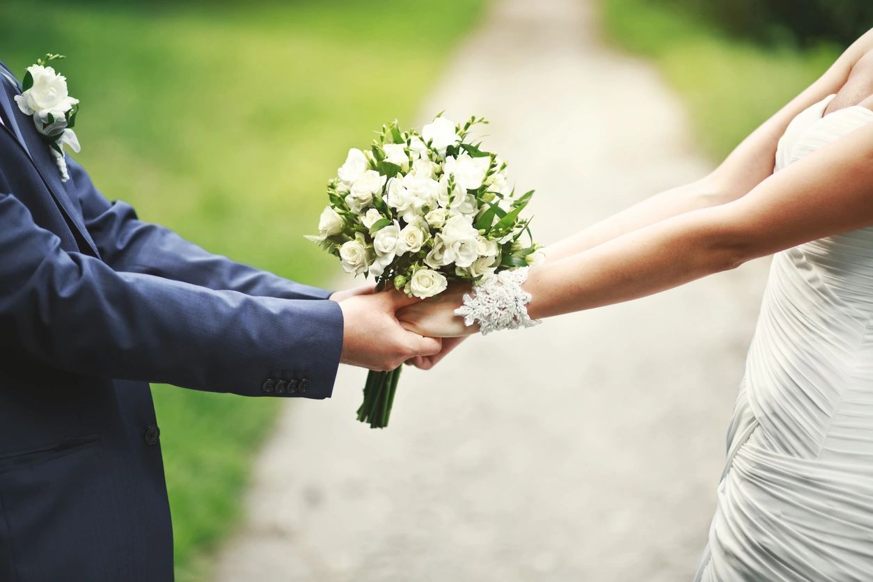 Newlyweds holding hands and flower bouquet