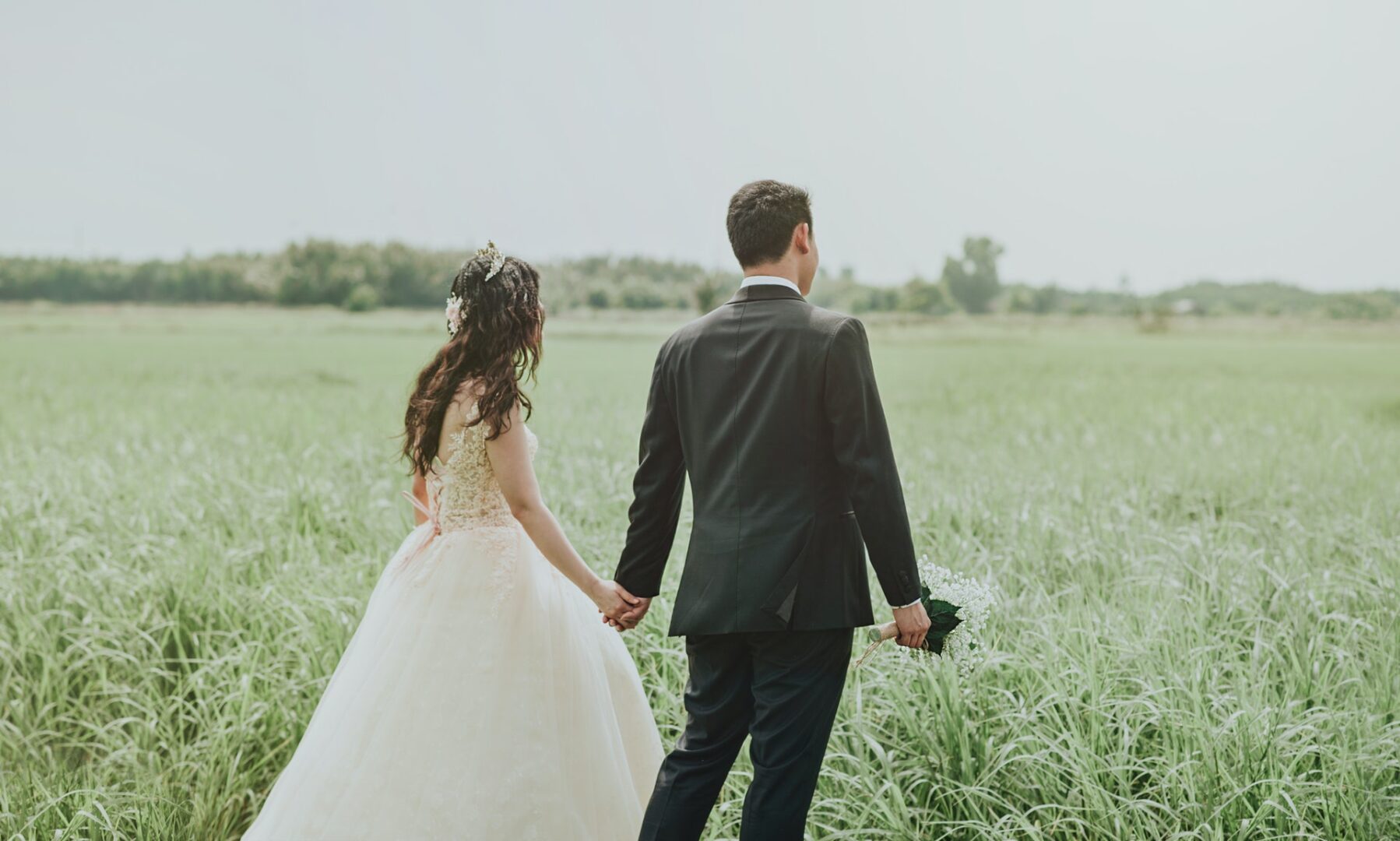 Newlyweds holding hands in field in Katy Texas